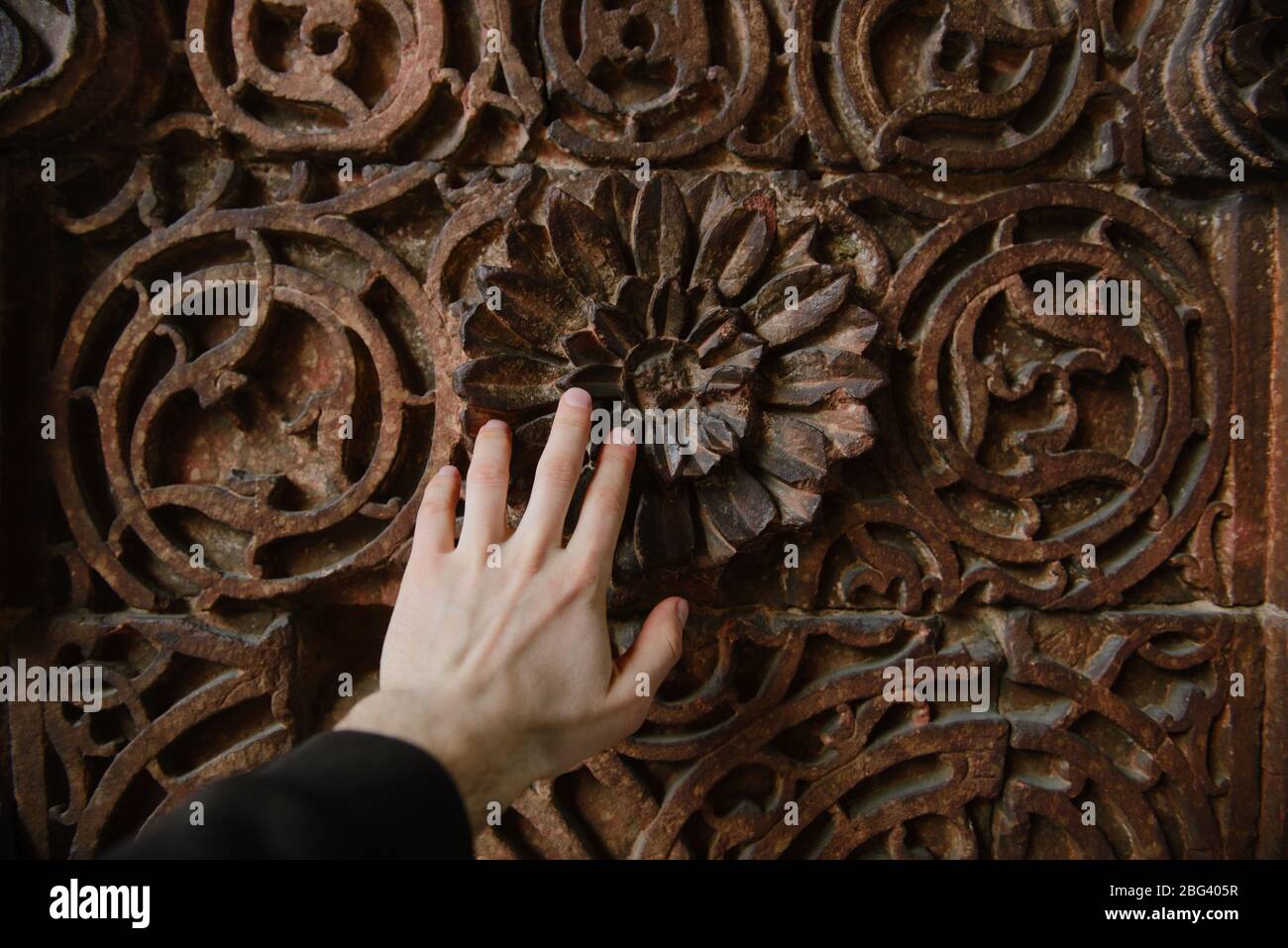 Mano dell'uomo che tocca una porta ornata, Forte Rosso, Delhi, India Foto Stock