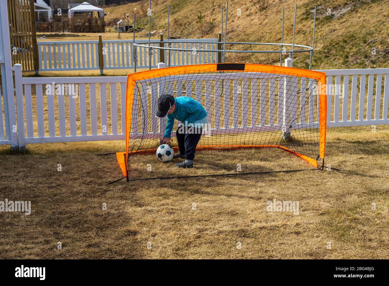 Rimani a casa. COVID 19. Vista ravvicinata del ragazzo che gioca a calcio sul cortile. Concetto di giochi all'aperto. Foto Stock