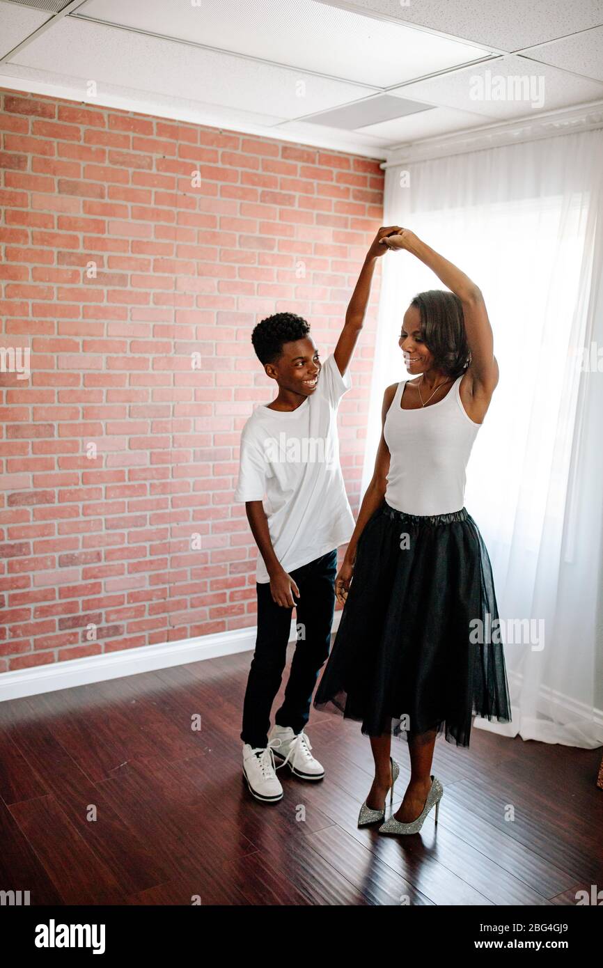 Preteen ragazzo nero che balla con mamma in tulle gonna e tacco a punta Foto Stock