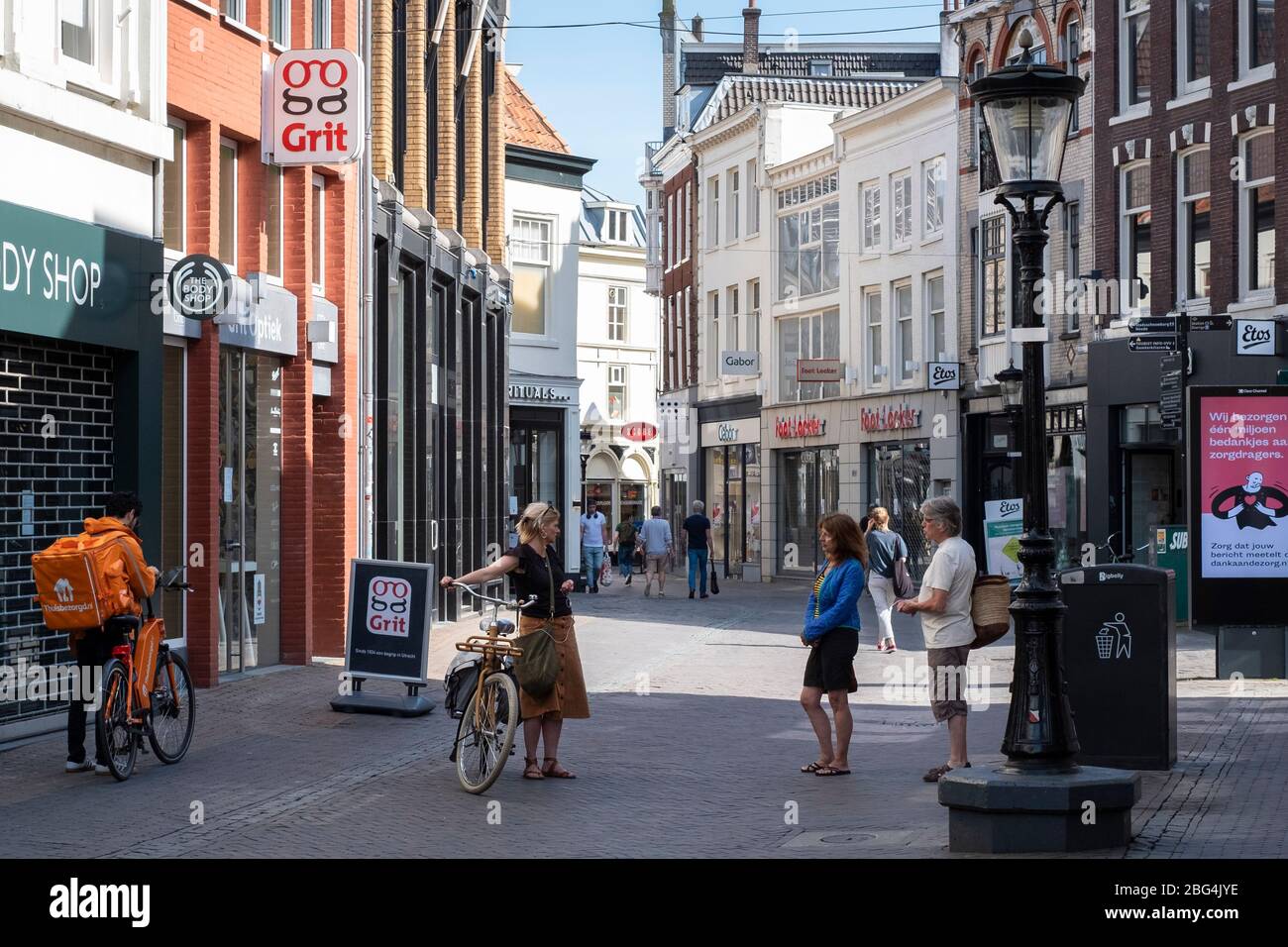 Crisi di Corona: La gente mantiene la distanza (1.5 metri) nel centro storico di Utrecht, Paesi Bassi. Sinistra: Un liberatore di Takeaway (Thuisbezorgd). Foto Stock