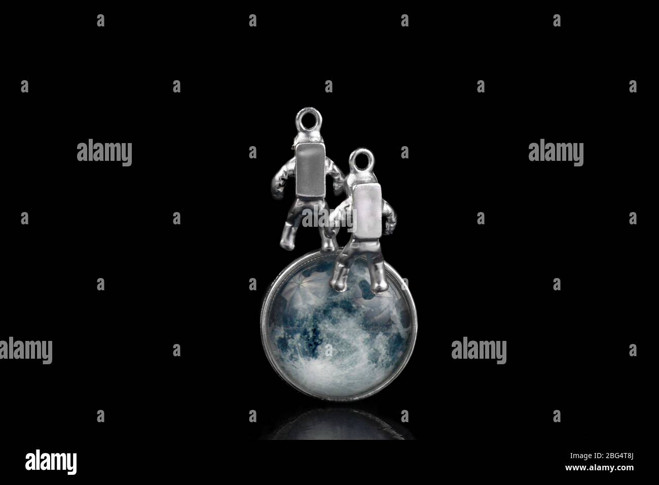 Due astronauti in miniatura che galleggiano nello spazio contro il volto della Luna. Primo piano, isolato su nero. Foto Stock