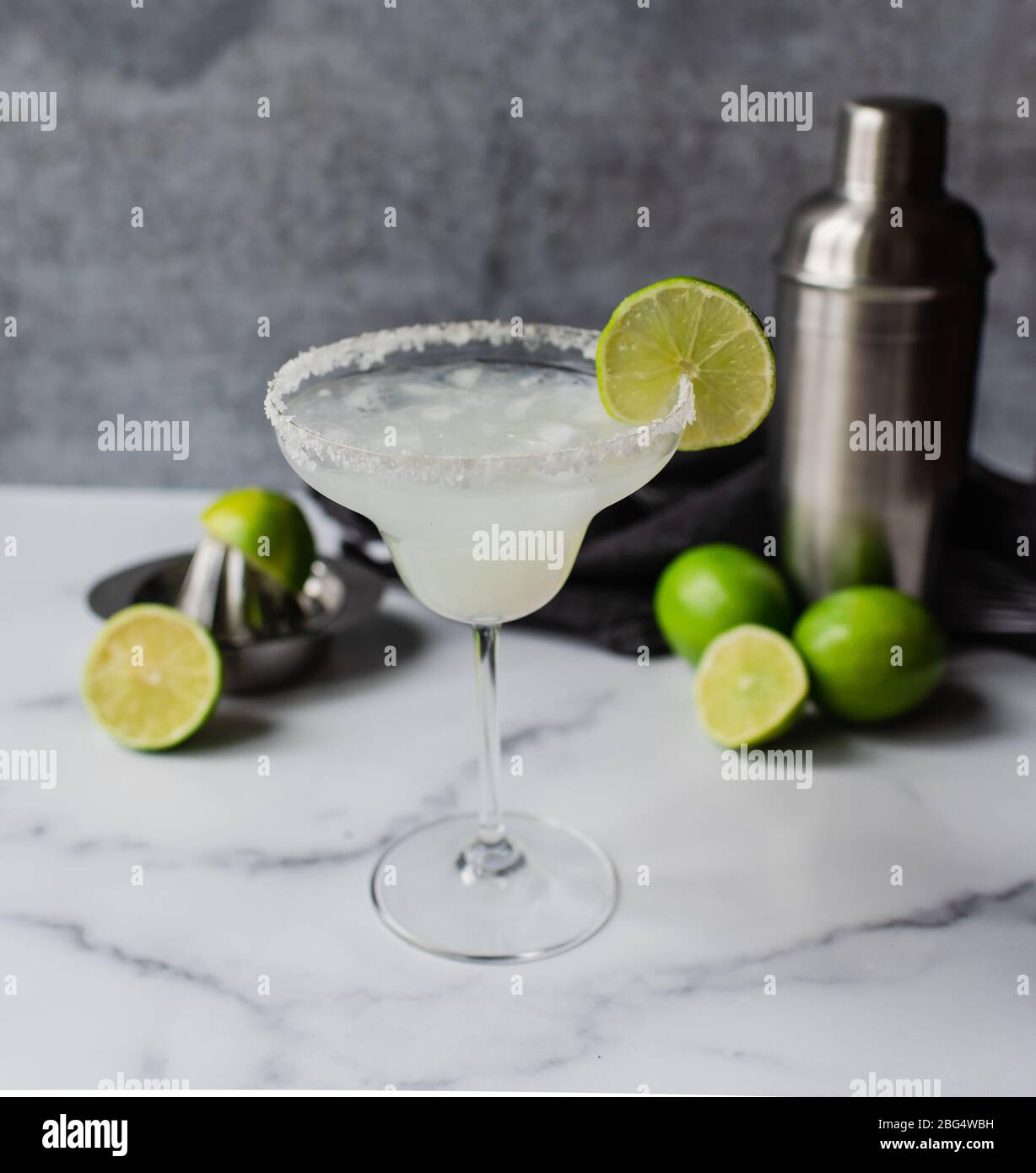 Primo piano del cocktail margarita con lime e shaker su bancone in marmo Foto Stock