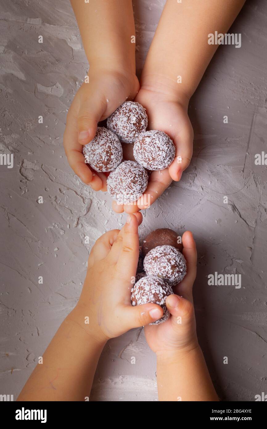 cioccolato vegano fatto in casa con scaglie di cocco nelle mani dei bambini. Disposizione piatta. Senza glutine Foto Stock