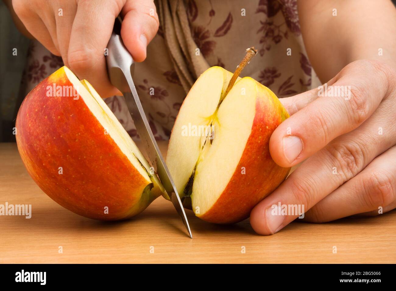 mani che tagliano una mela con un coltello Foto Stock