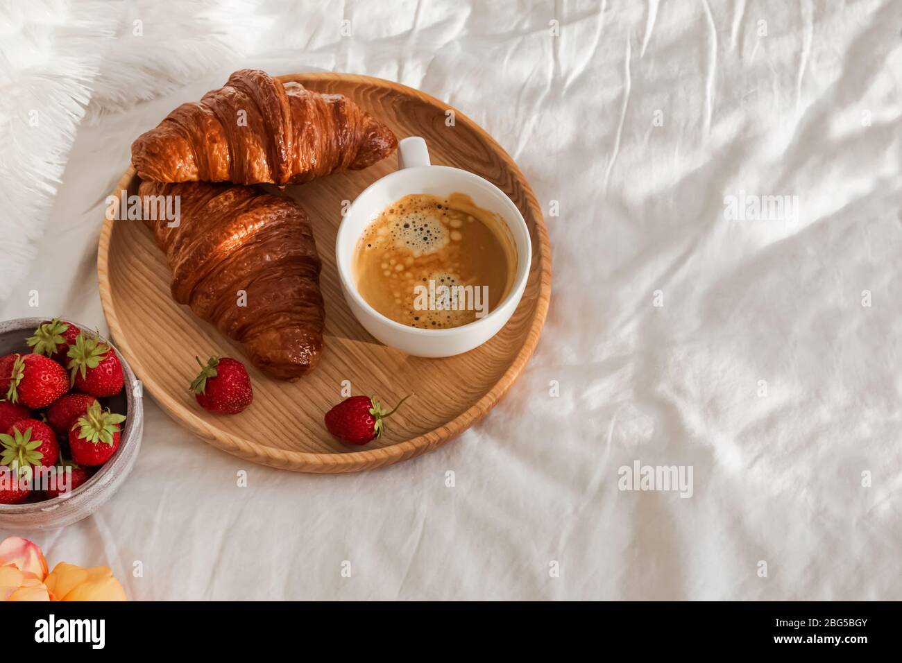 Colazione a letto, vassoio con tazza di caffè, croissant freschi e fragole Foto Stock
