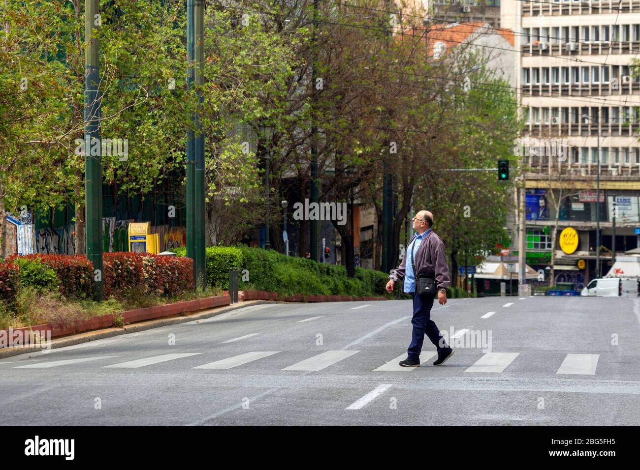 Un Athenian passeggiate durante il blocco in via Panepistimiou, uno dei viali più trafficati di Atene, Grecia, quasi vuoto ora durante lo scoppio del coronavirus. Foto Stock