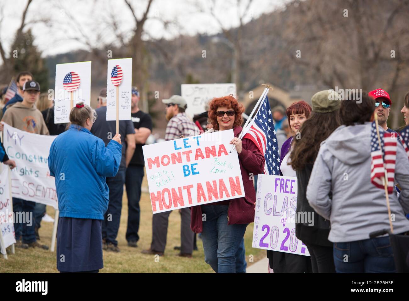 Helena, Montana - 19 aprile 2020: Donna rossa capeggiata tenendo un segno che vuole tornare al lavoro a causa della chiusura di Coronavirus delle imprese. Protestare un Foto Stock