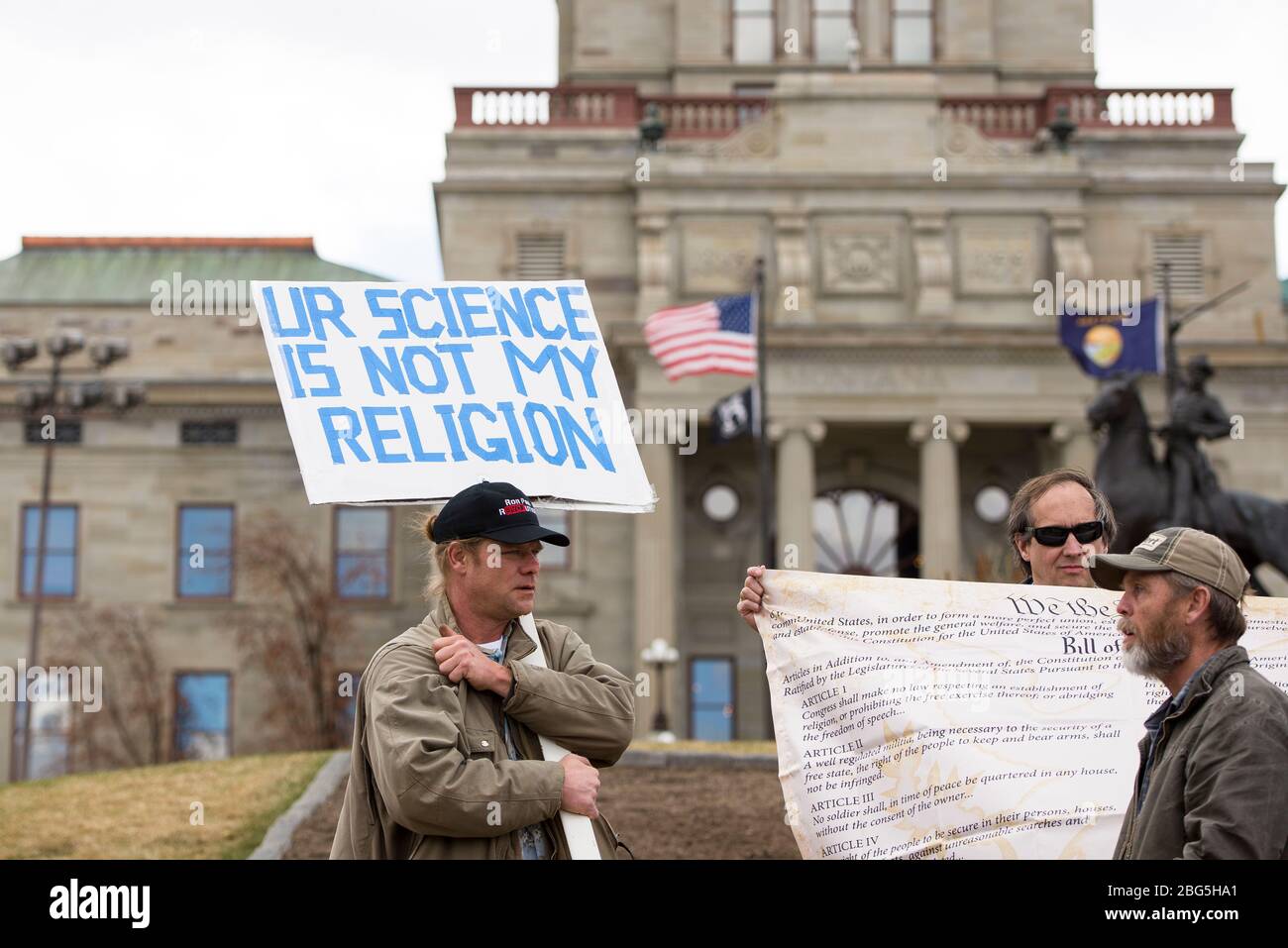 Helena, Montana - 19 aprile 2020: Un uomo che protestava portando un cappello che porta una scienza non è il mio segno religioso ad un raduno di arresto di Coronavirus al Cap Foto Stock