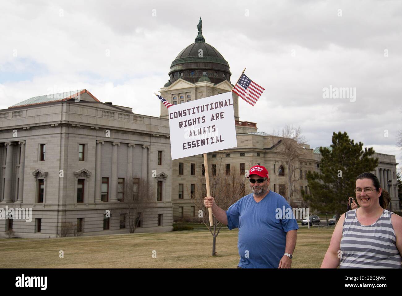 Helena, Montana - 19 aprile 2020: Uomo che protesta indossando rendere l'America grande ancora una volta cappello che detiene diritti costituzionali sono segno essenziale a una protesta ag Foto Stock