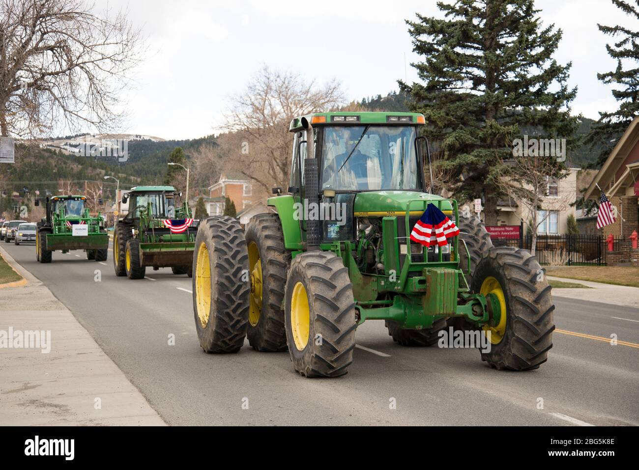 Helena, Montana - 19 aprile 2020: Agricoltori in trattori verdi decorati con bandiera americana intorno alla piazza del Campidoglio protestando contro il governo Foto Stock