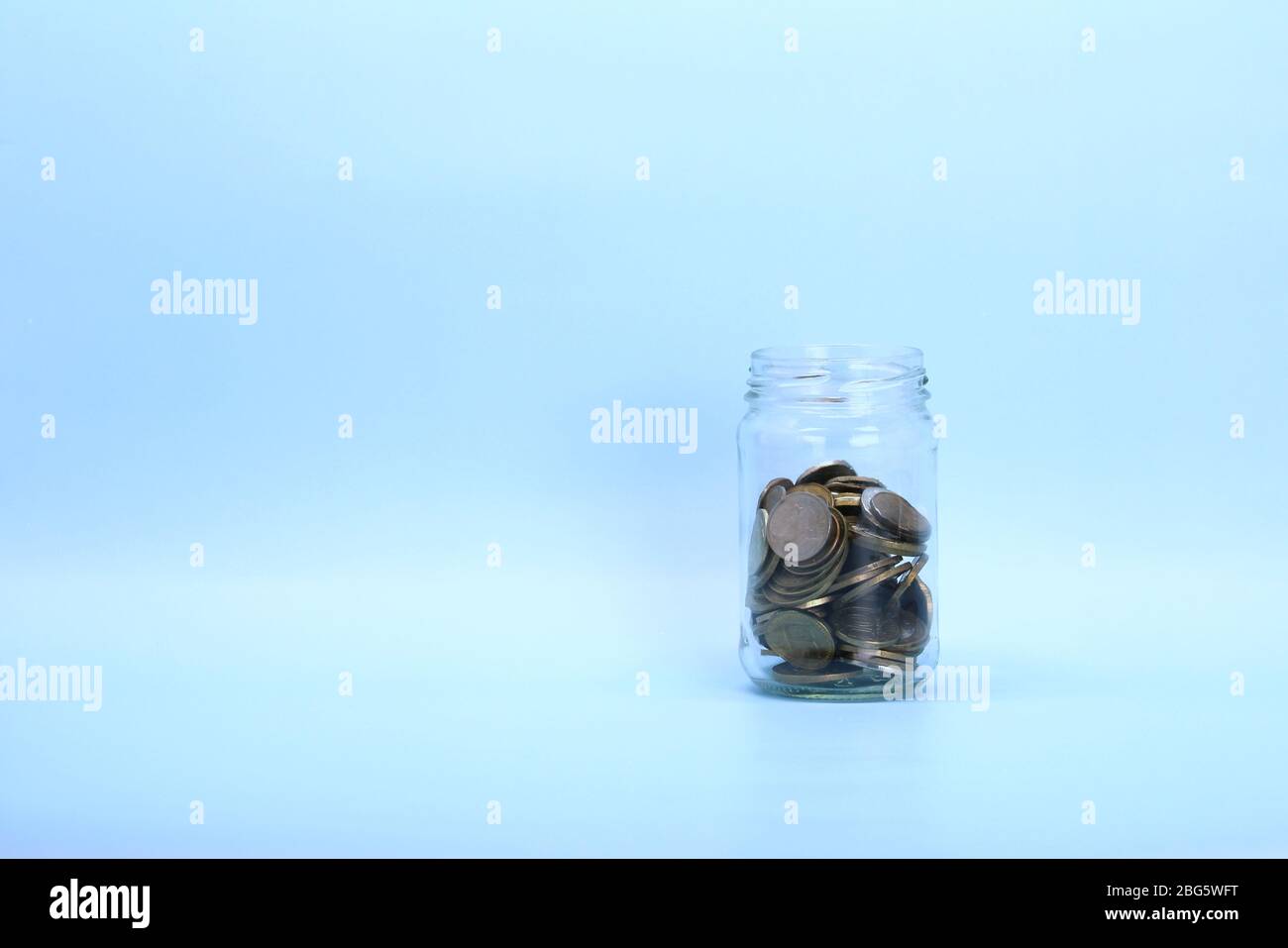Monete metalliche, rubli russi, giacciono in un vaso di vetro trasparente su uno sfondo chiaro. Posizionare per testo e disegno. Foto Stock