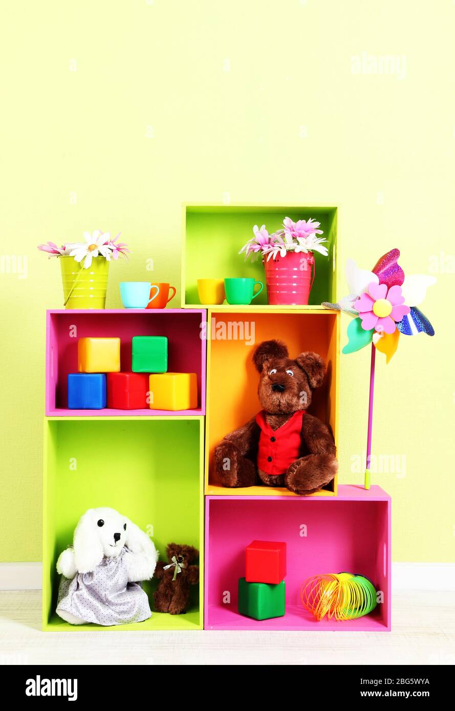 Scaffali luminosi di colori diversi con giocattoli sullo sfondo della parete Foto Stock