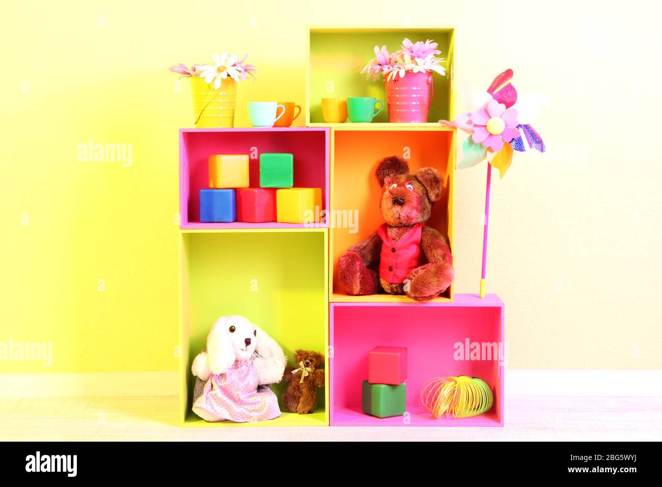 Scaffali luminosi di colori diversi con giocattoli sullo sfondo della parete Foto Stock