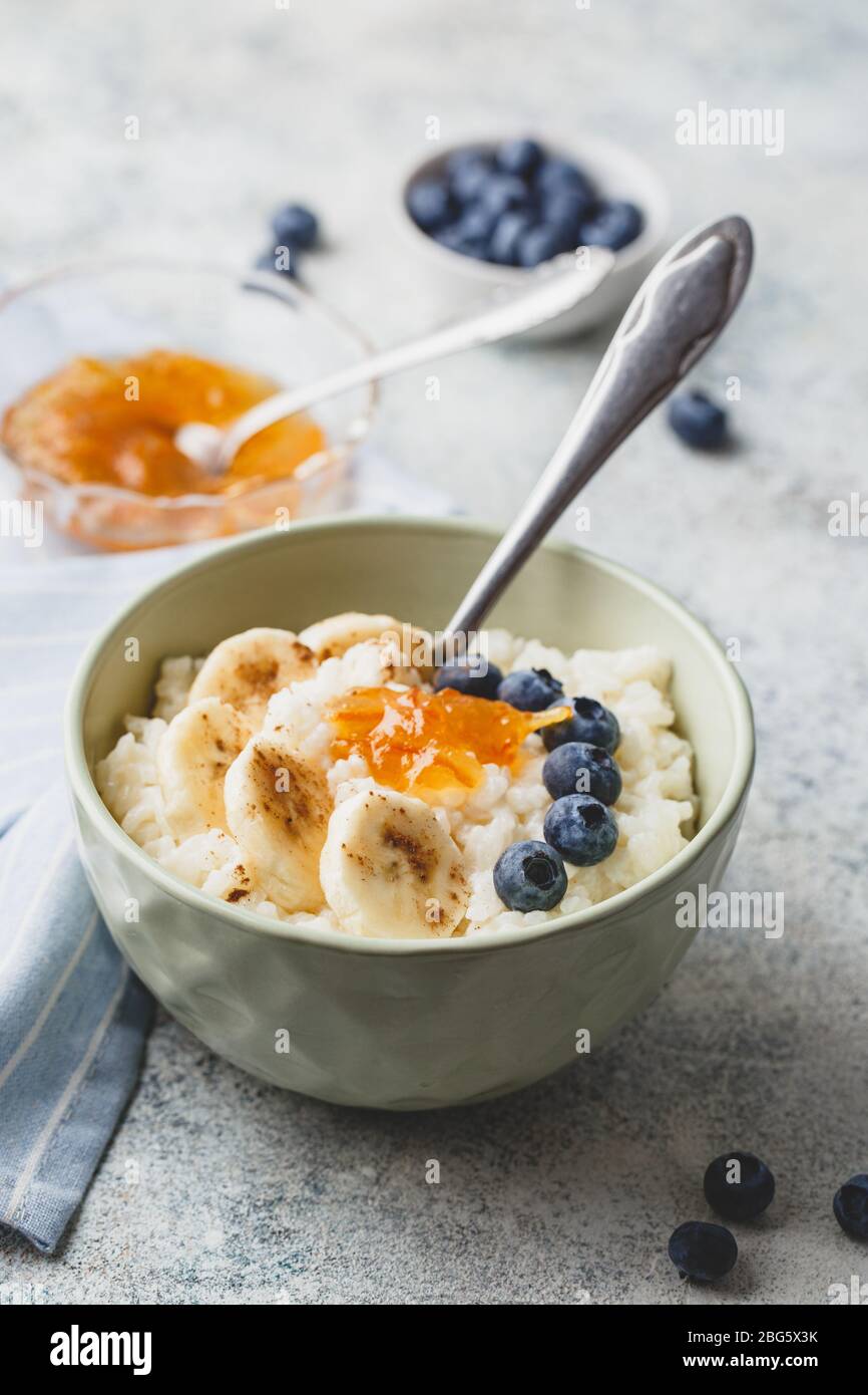 Colazione con Porridge di riso Al Latte con banani, confettura di mirtilli e arance, budino di riso cremoso o riz au lait francese in una ciotola Foto Stock