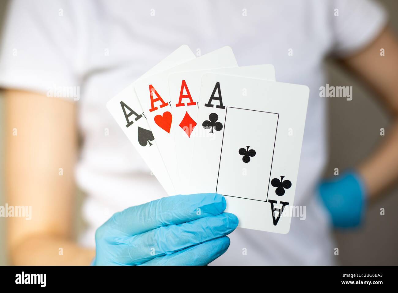 Donna Yound con guanti protettivi usa e getta che regge carte - quattro assi, quattro del genere Foto Stock