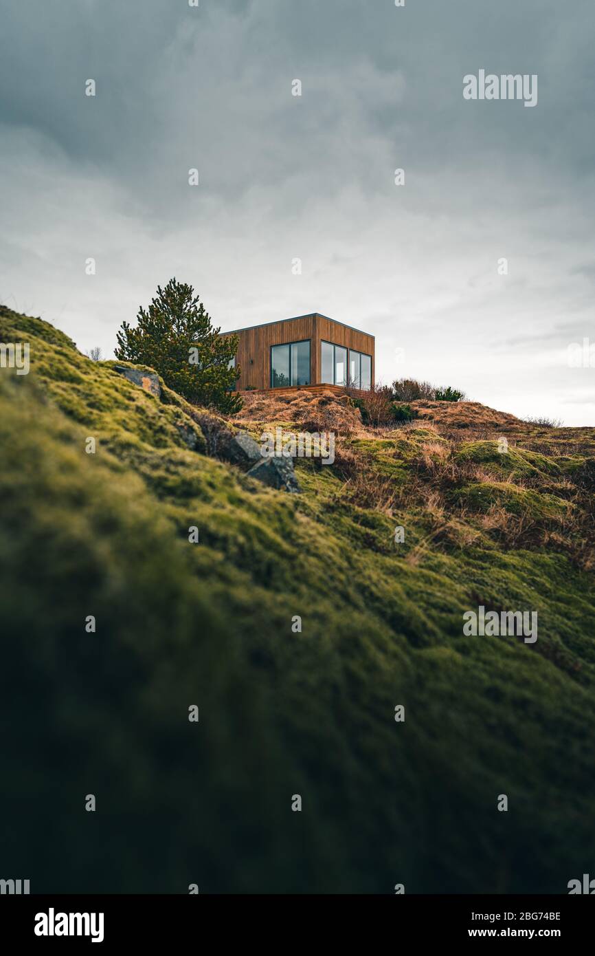 Una piccola casa su una collina erbosa perfetta per una vacanza isolata o semplicemente un tranquillo relax in connessione con la natura. Architettura moderna nel Foto Stock