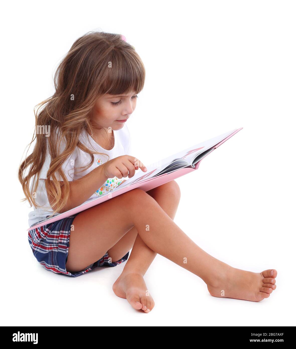 Bambina seduta sul pavimento con libro isolato su bianco Foto Stock