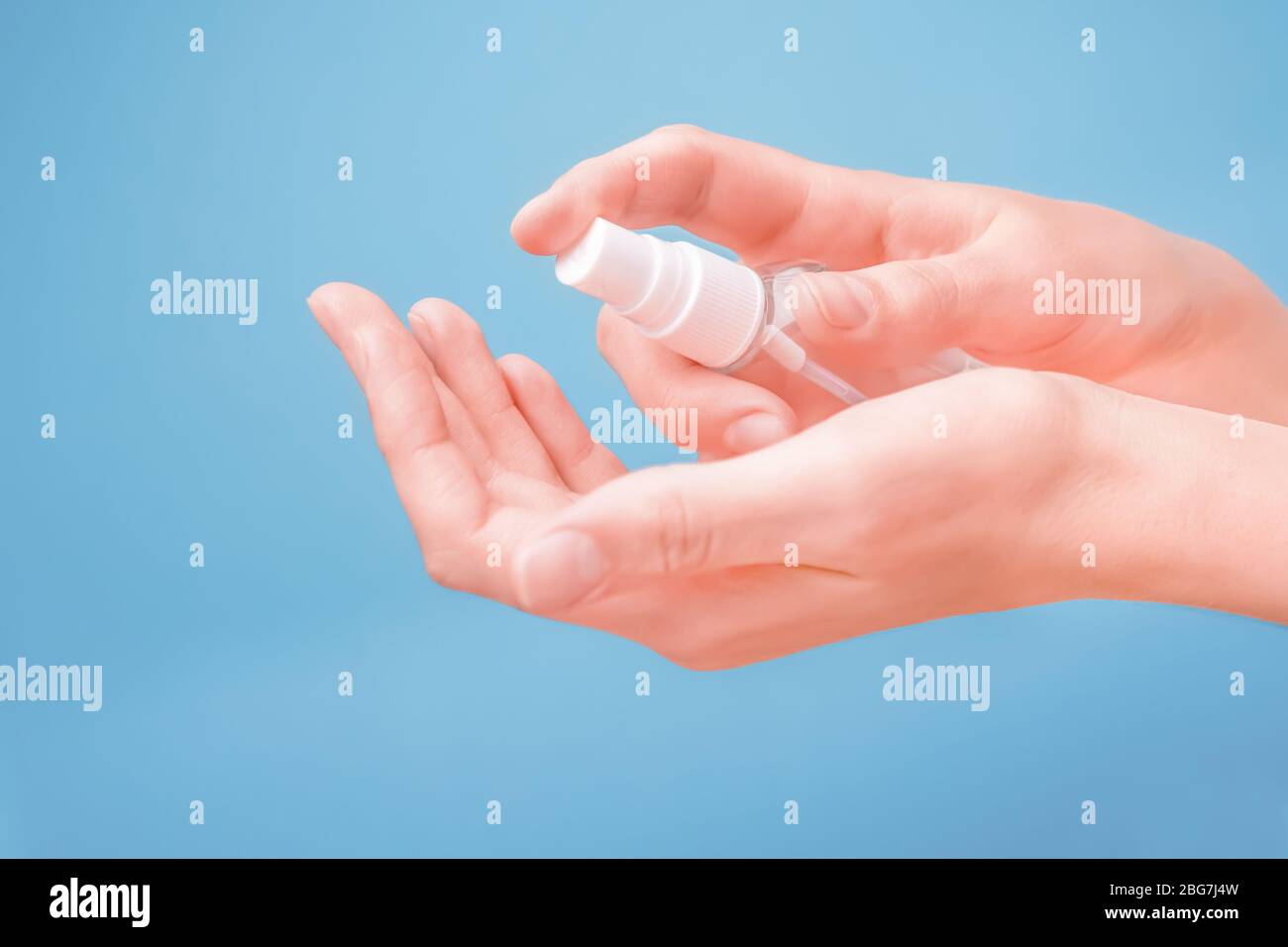 Pulizia mani su sfondo blu. Primo piano del concetto di disinfezione delle mani. Pulizia delle mani da virus, batteri, germi con agente decontaminante con alcool Foto Stock