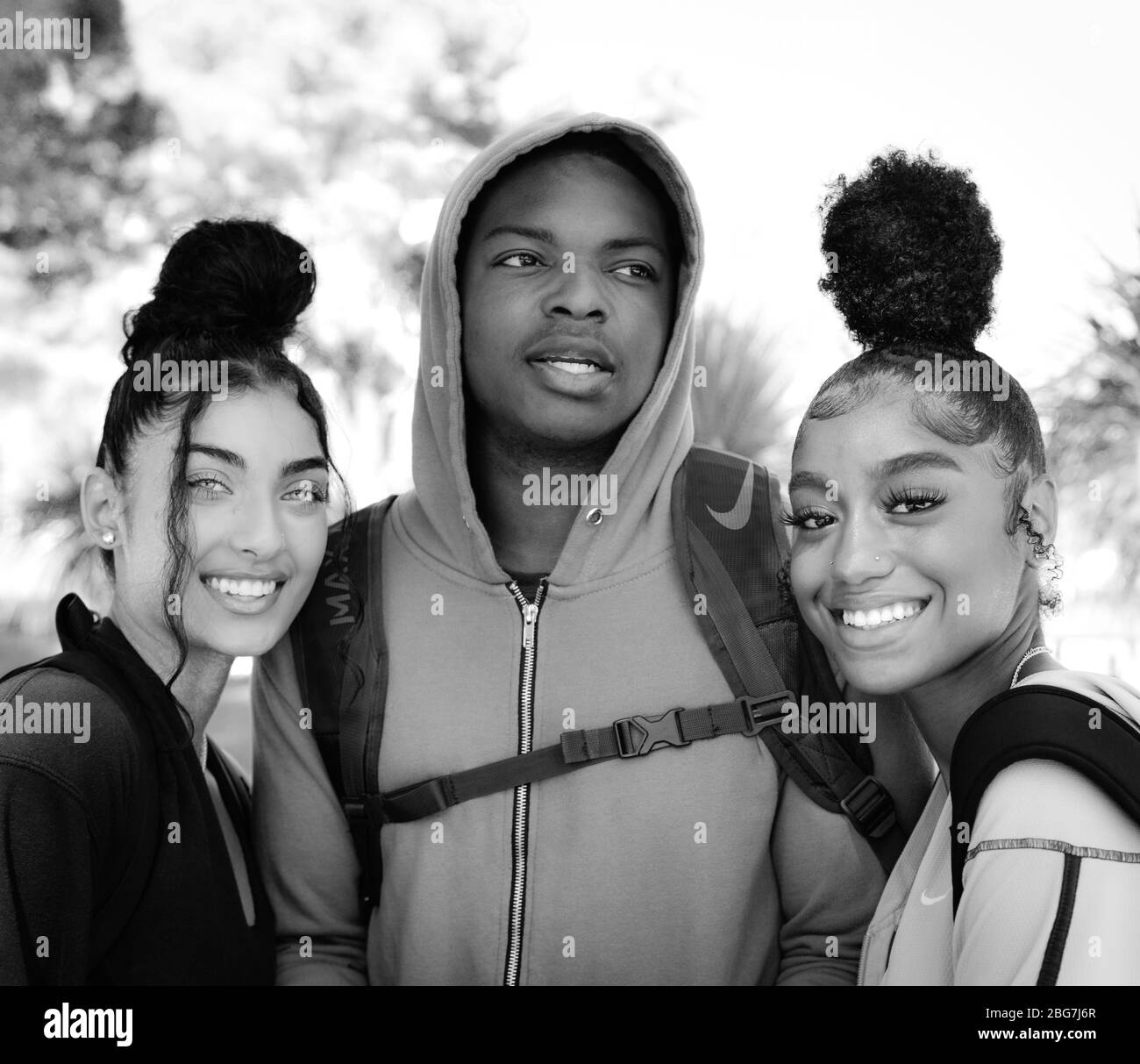 Belle giovani donne e uomo di colore, godere della vita del campus come studenti con felpa e capelli alla moda updo e sorrisi in Arizona, Stati Uniti, in nero e. Foto Stock