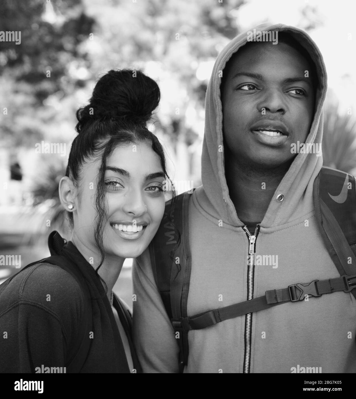 Una giovane donna e un uomo di colore adorabile, godetevi la vita del campus come studenti con felpa con cappuccio e capelli trendy up-do e sorride alla U di A a Tucson, Arizona Foto Stock