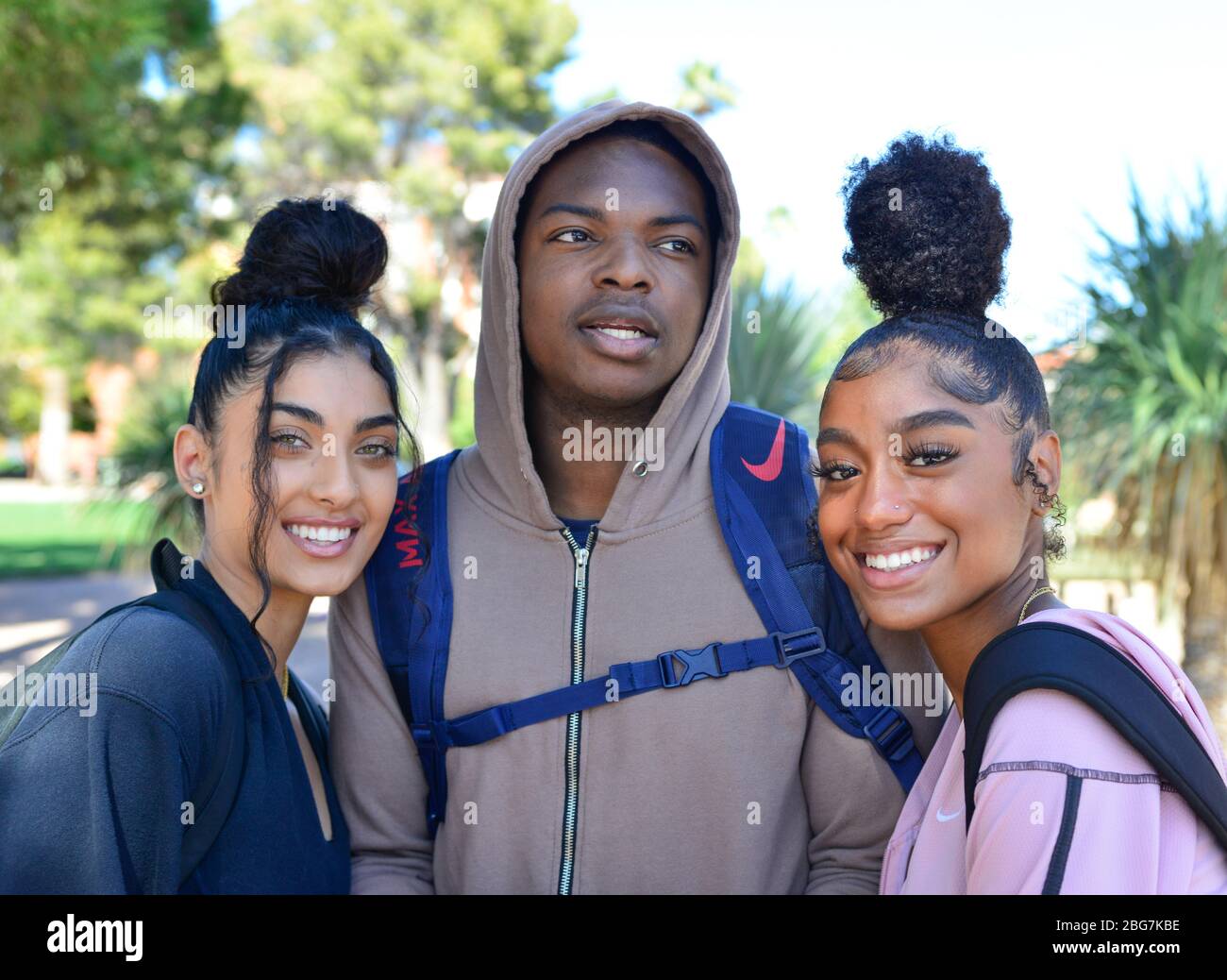 Belle giovani donne e uomo di colore, godere della vita del campus come studenti con felpa e capelli alla moda updo e sorrisi in Arizona, Stati Uniti, Foto Stock