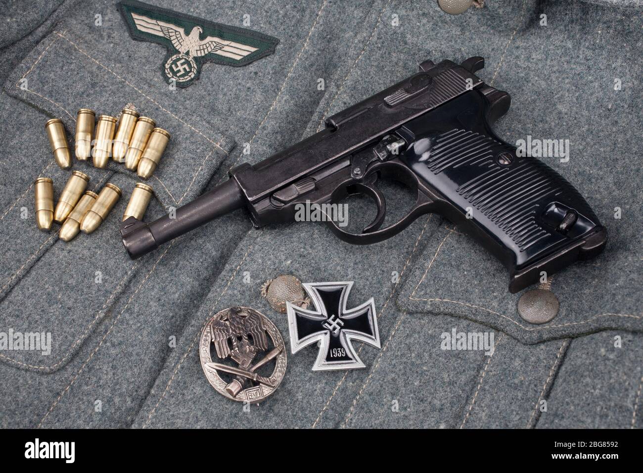 Era la seconda guerra mondiale l'esercito tedesco nazista 9 mm pistola semiautomatica con Iron Cross premio su sfondo grigio esercito uniforme Foto Stock
