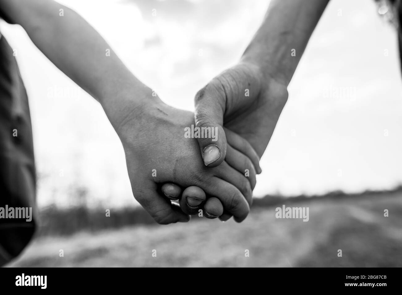 I bambini tengono le mani insieme su una passeggiata in una giornata estiva. Foto in bianco e nero. Foto Stock
