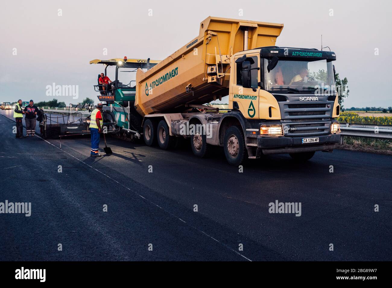 lavoratori edili su strada che utilizzano la pavimentazione. manutenzione autostradale, asfaltatrice che stendono nuovo asfalto o bitume durante la costruzione di autostrade Foto Stock
