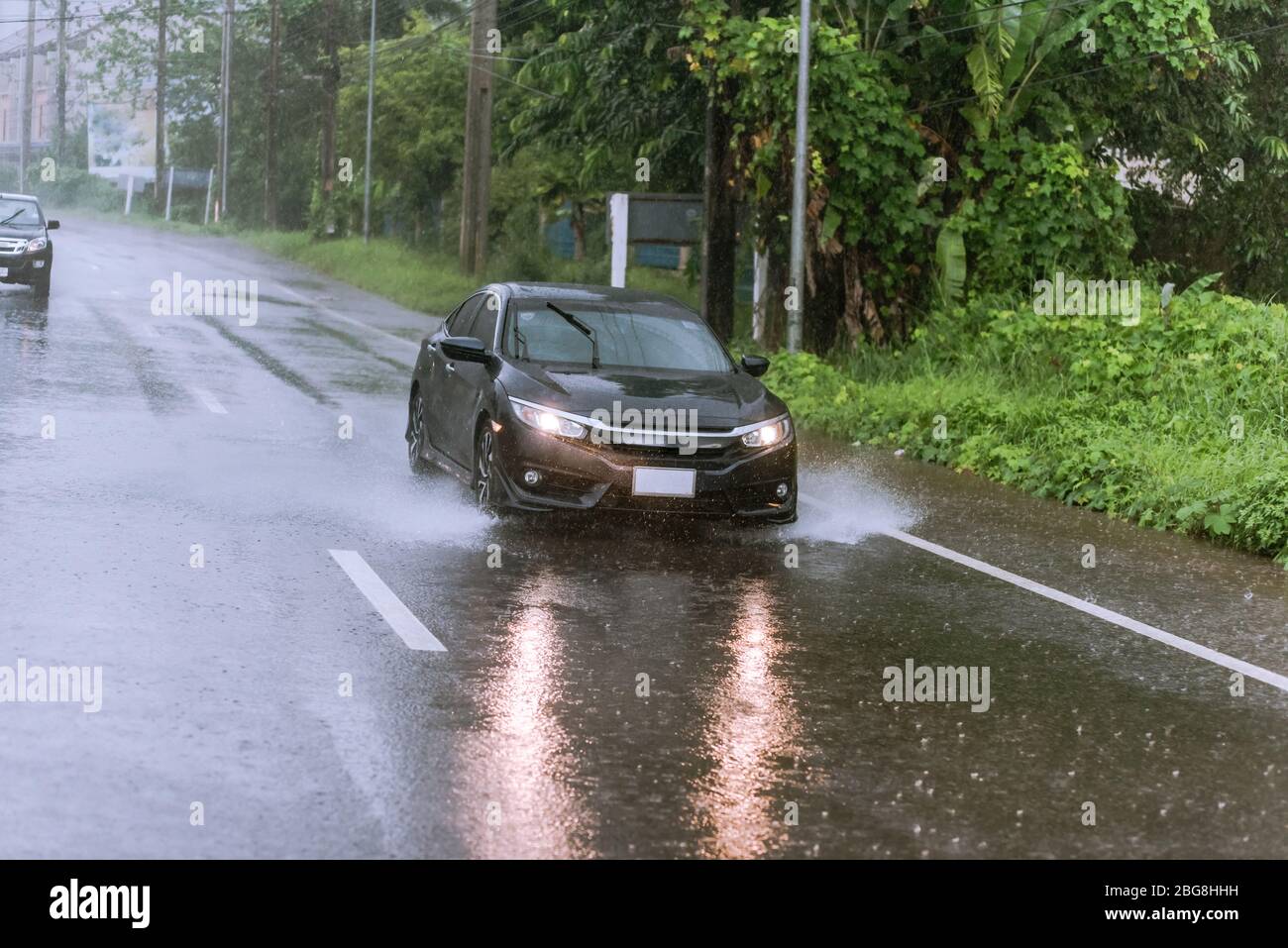 Auto che guidano su strada bagnata sotto la pioggia Foto Stock