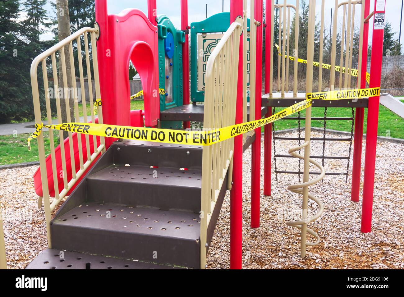 Attenzione non inserire il nastro giallo avvolto intorno all'apparecchiatura del parco giochi durante la pandemia Covid-19. Foto Stock