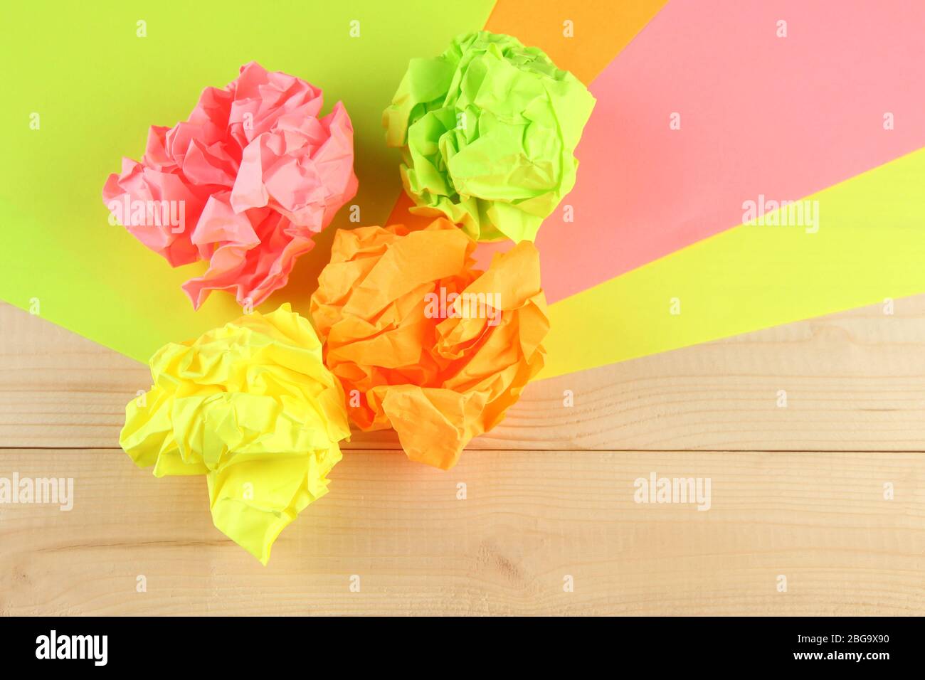 Palline di carta colorate e sbriciolate su sfondo di legno Foto Stock