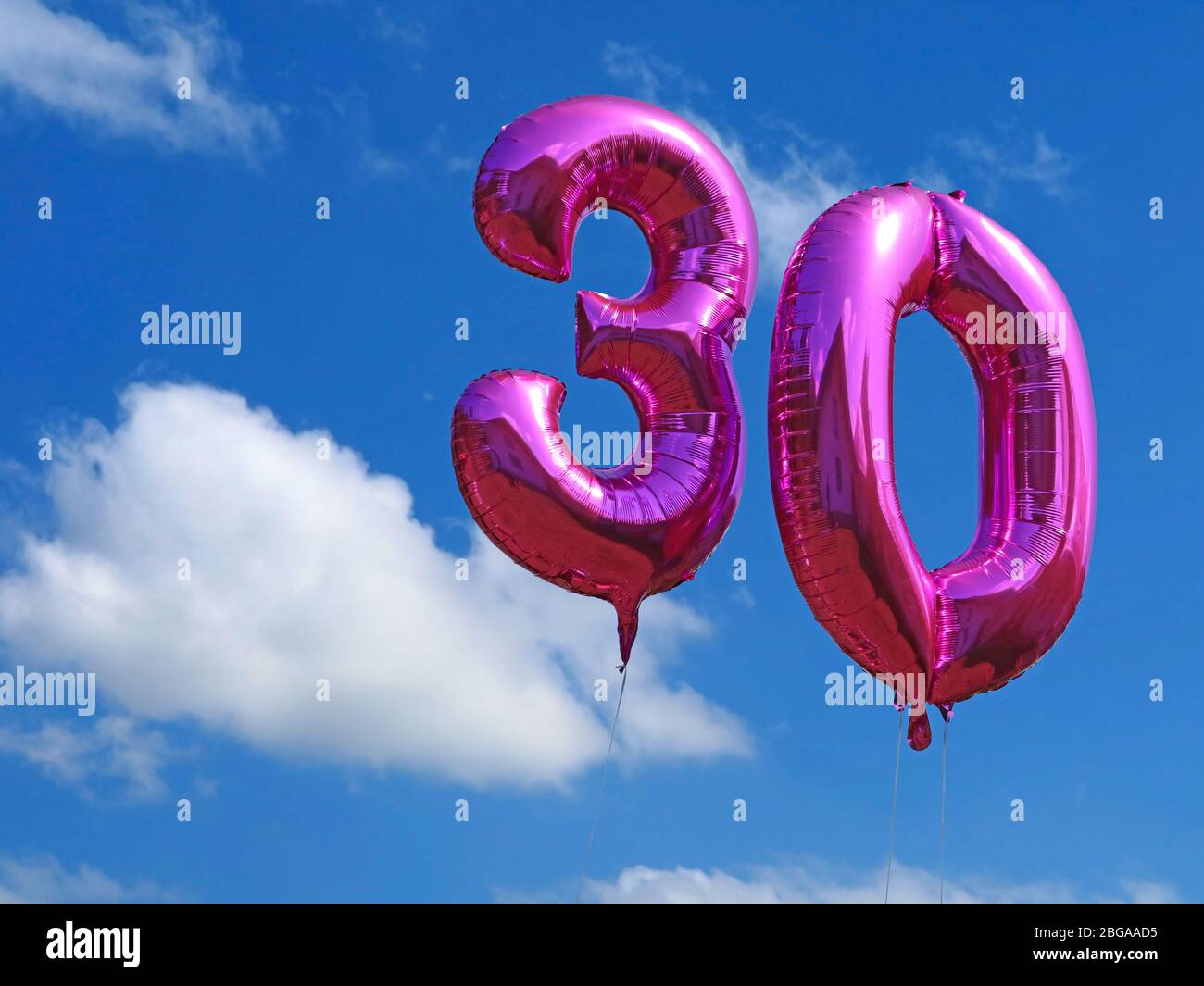 palloncini di elio rosa su cielo nuvoloso blu, celebrando i trenta anni con palloncini numero, sfondo compleanno Foto Stock
