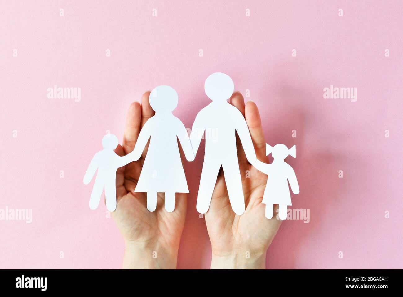 Donna in possesso di carta famiglia in mani vista superiore su sfondo rosa. Concetto di amore e relazioni. Foto Stock