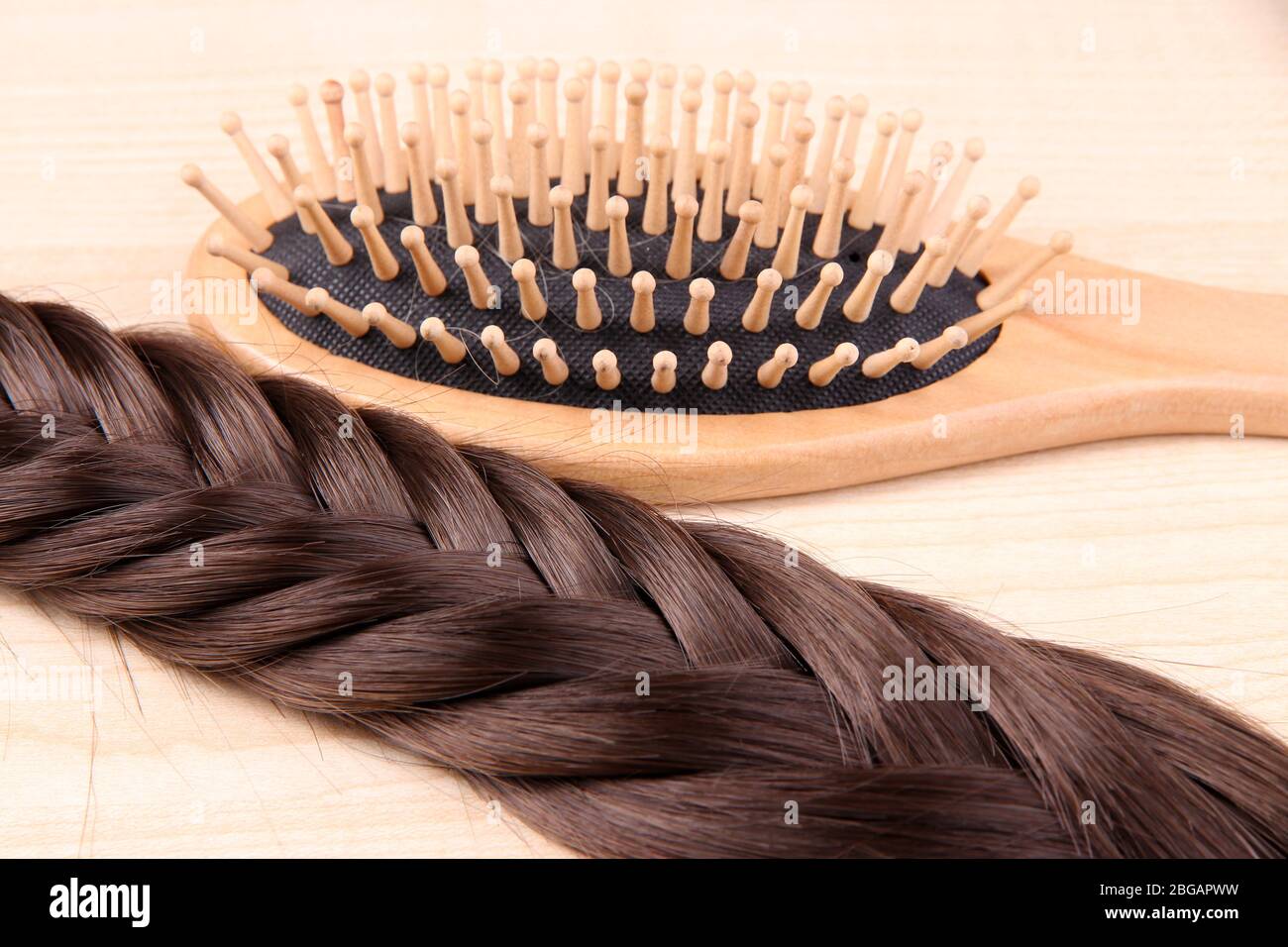 Capelli lunghi marroni con spazzola su sfondo legno Foto Stock