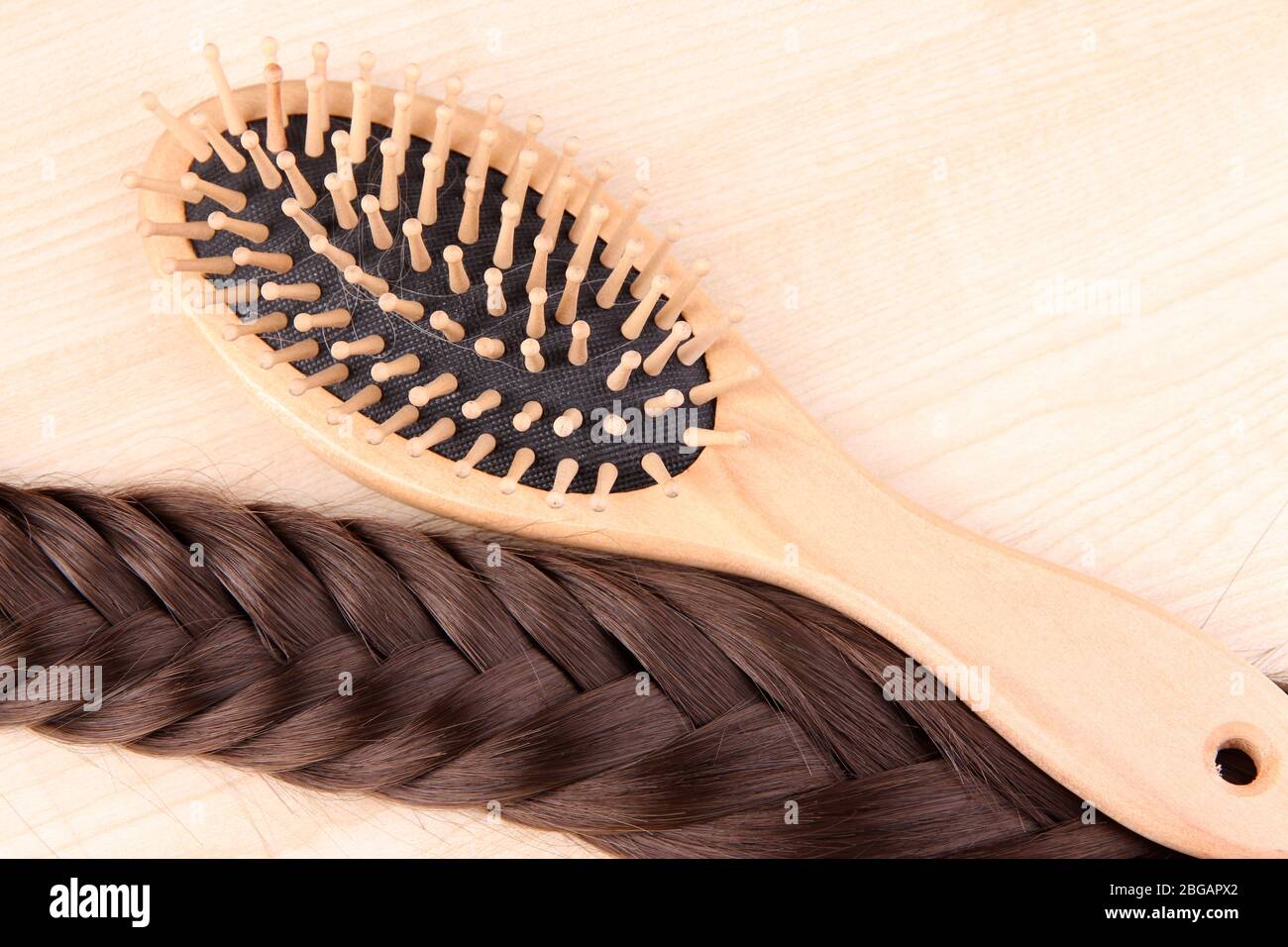 Capelli lunghi marroni con spazzola su sfondo legno Foto Stock
