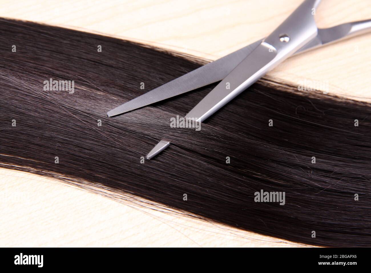 Capelli lunghi e forbici marroni su sfondo di legno Foto Stock