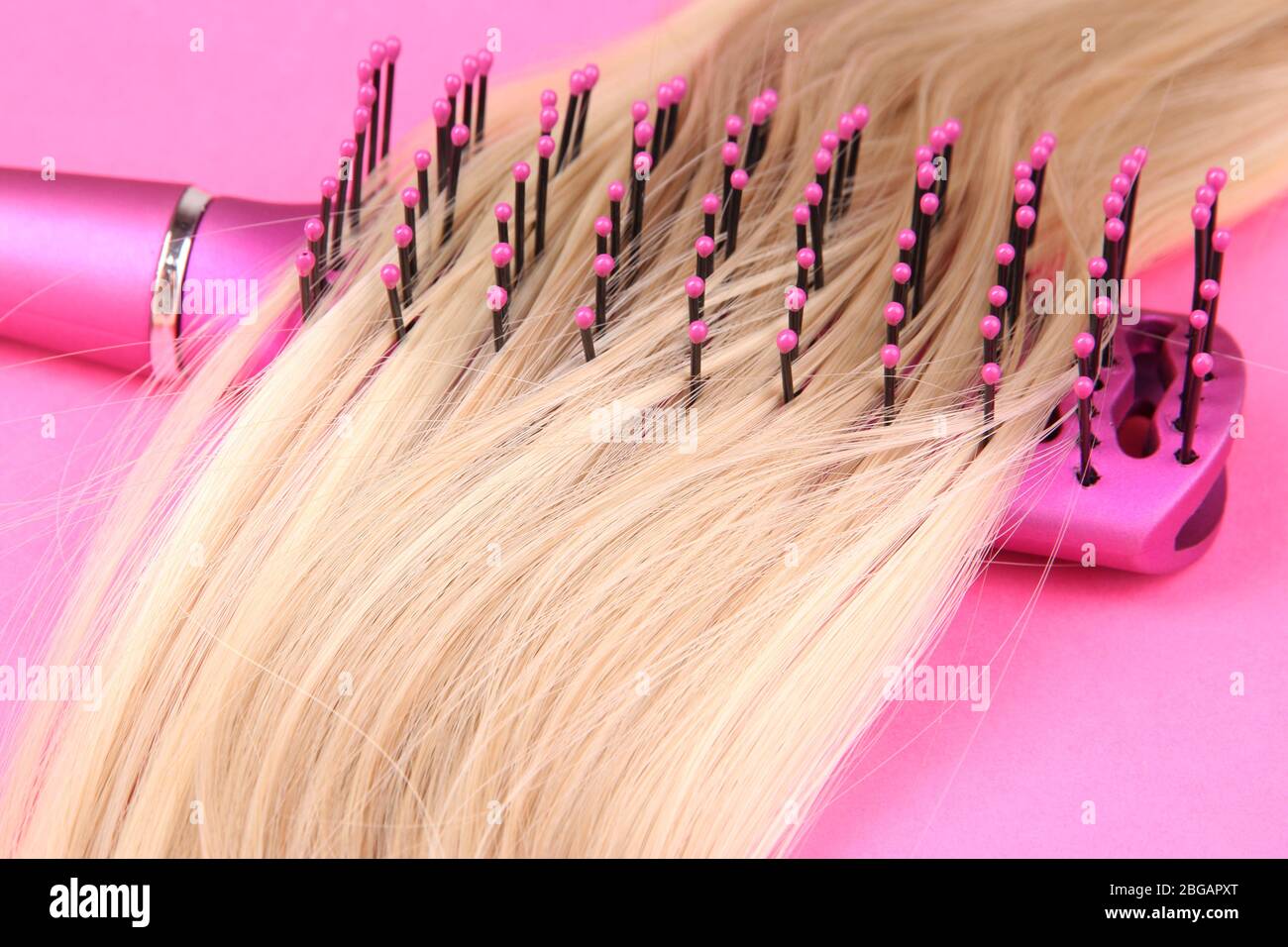 Capelli lunghi biondi con spazzola su sfondo rosa Foto Stock