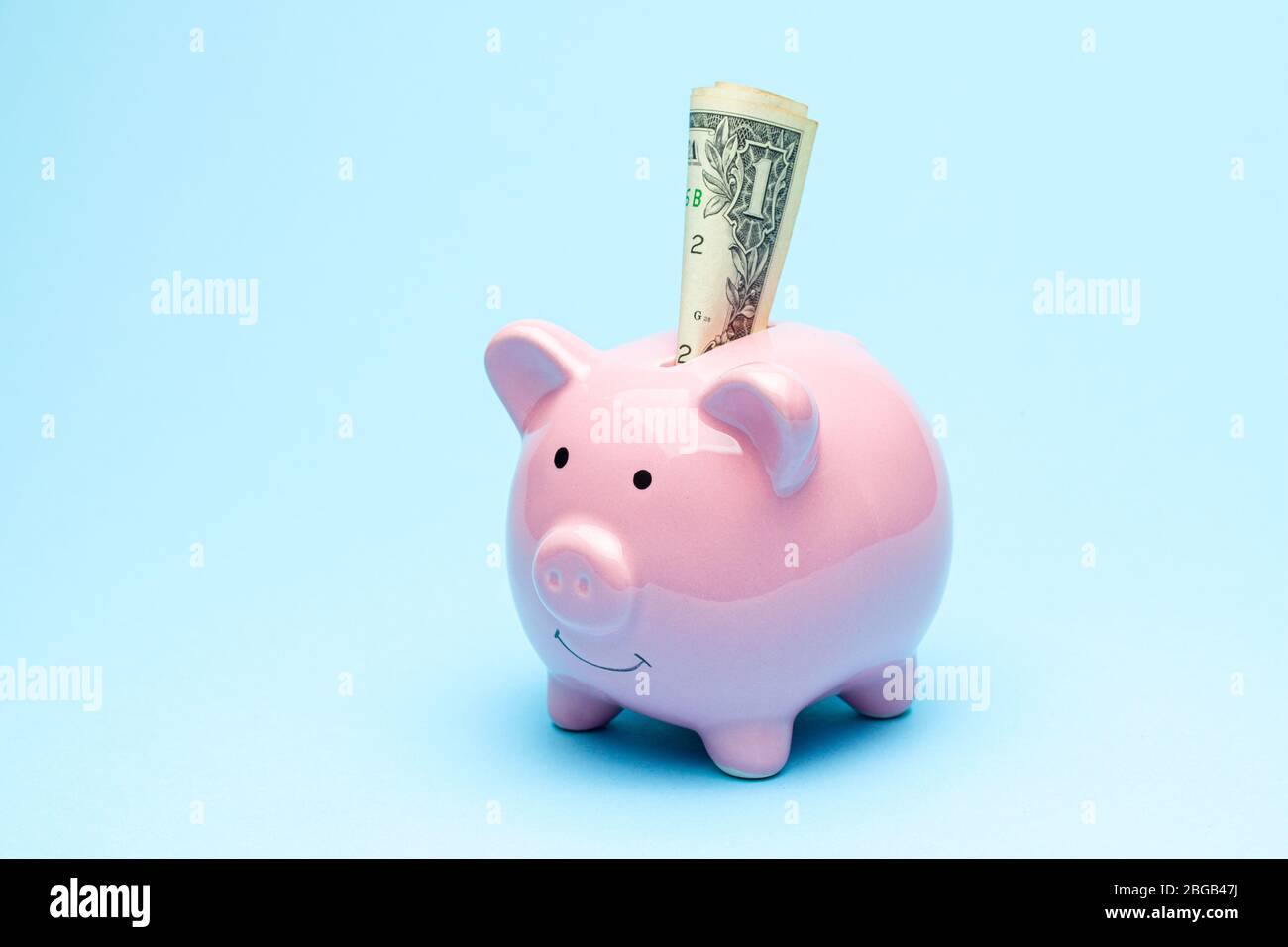 Piggy banca rosa e dollaro fattura su uno sfondo blu. Foto Stock