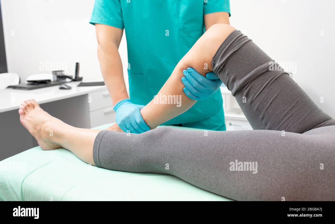 Fisioterapista che controlla la gamba del paziente nel reparto trauma della clinica. Primo piano della gamba del paziente ferita Foto Stock