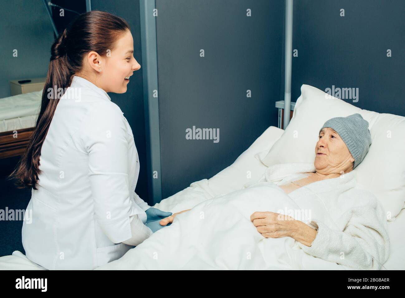 medico che comunica con un paziente in un reparto di clinica oncologica. Donna anziana che riceve chemioterapia attraverso la porta per infusione durante il trattamento del cancro Foto Stock