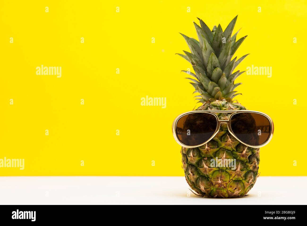 Frutta di ananas estiva con occhiali da sole su sfondo giallo brillante Foto Stock