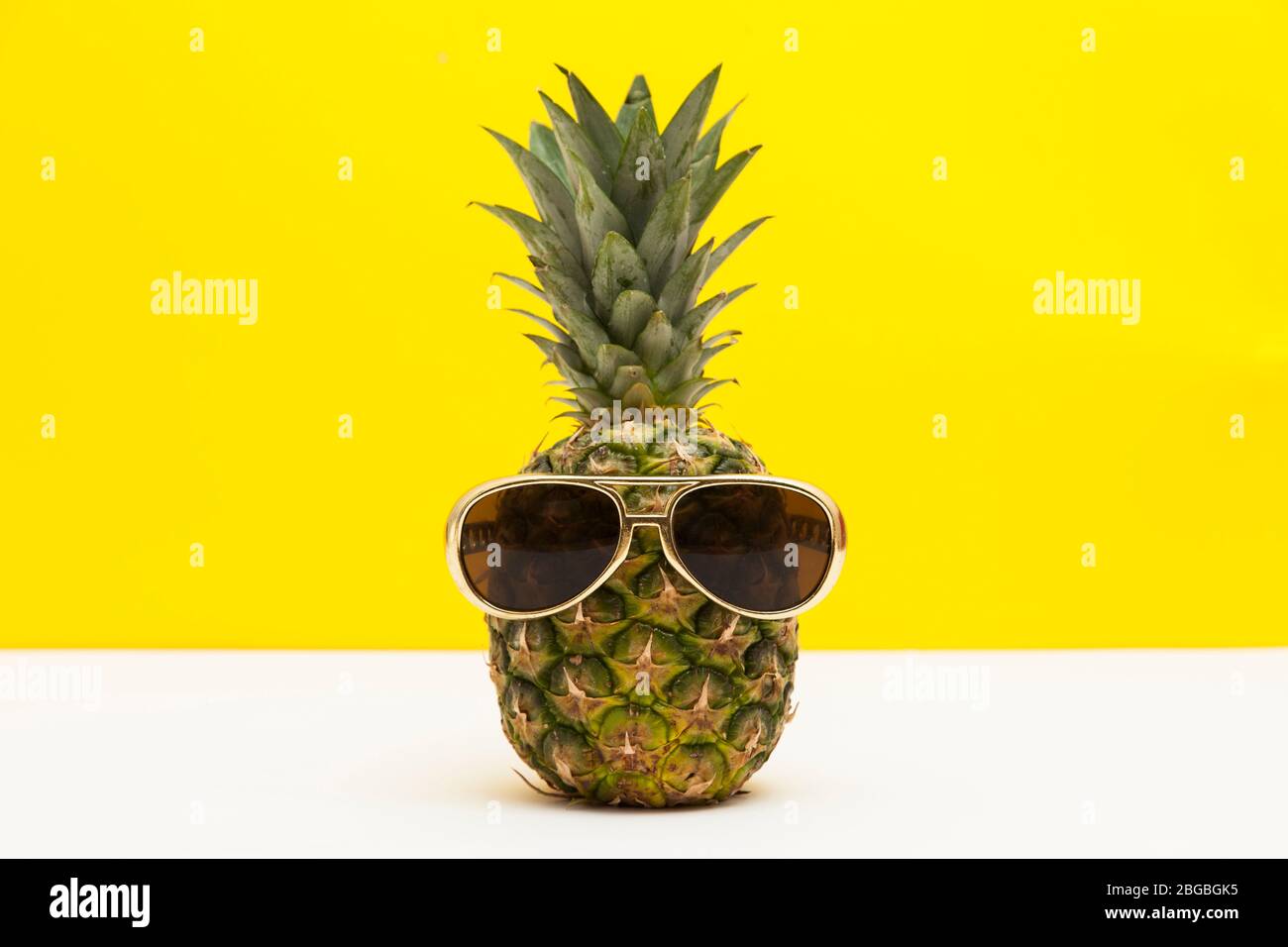 Frutta di ananas estiva con occhiali da sole su sfondo giallo brillante Foto Stock