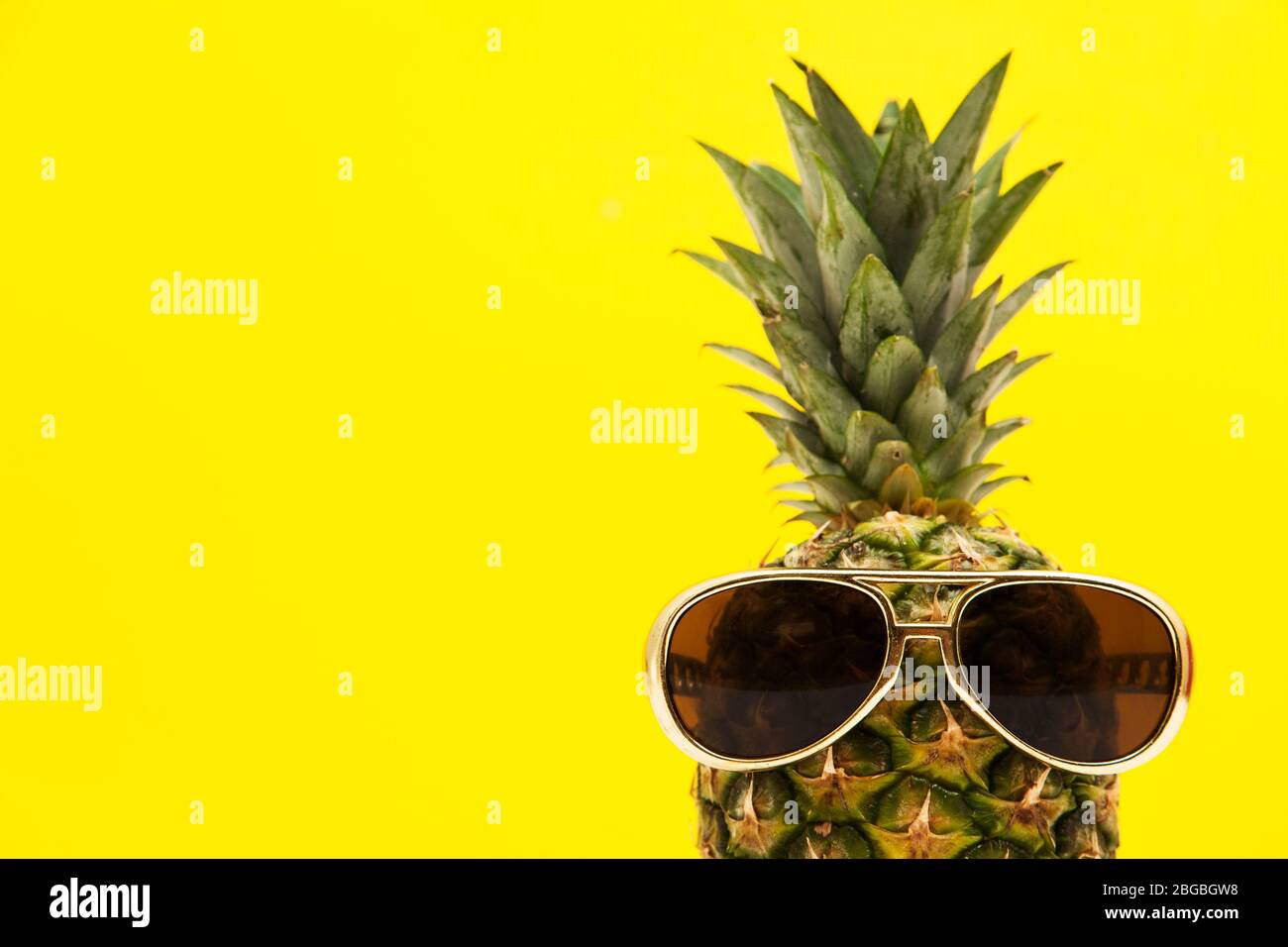 Frutta di ananas estiva con occhiali da sole su sfondo giallo brillante Foto Stock