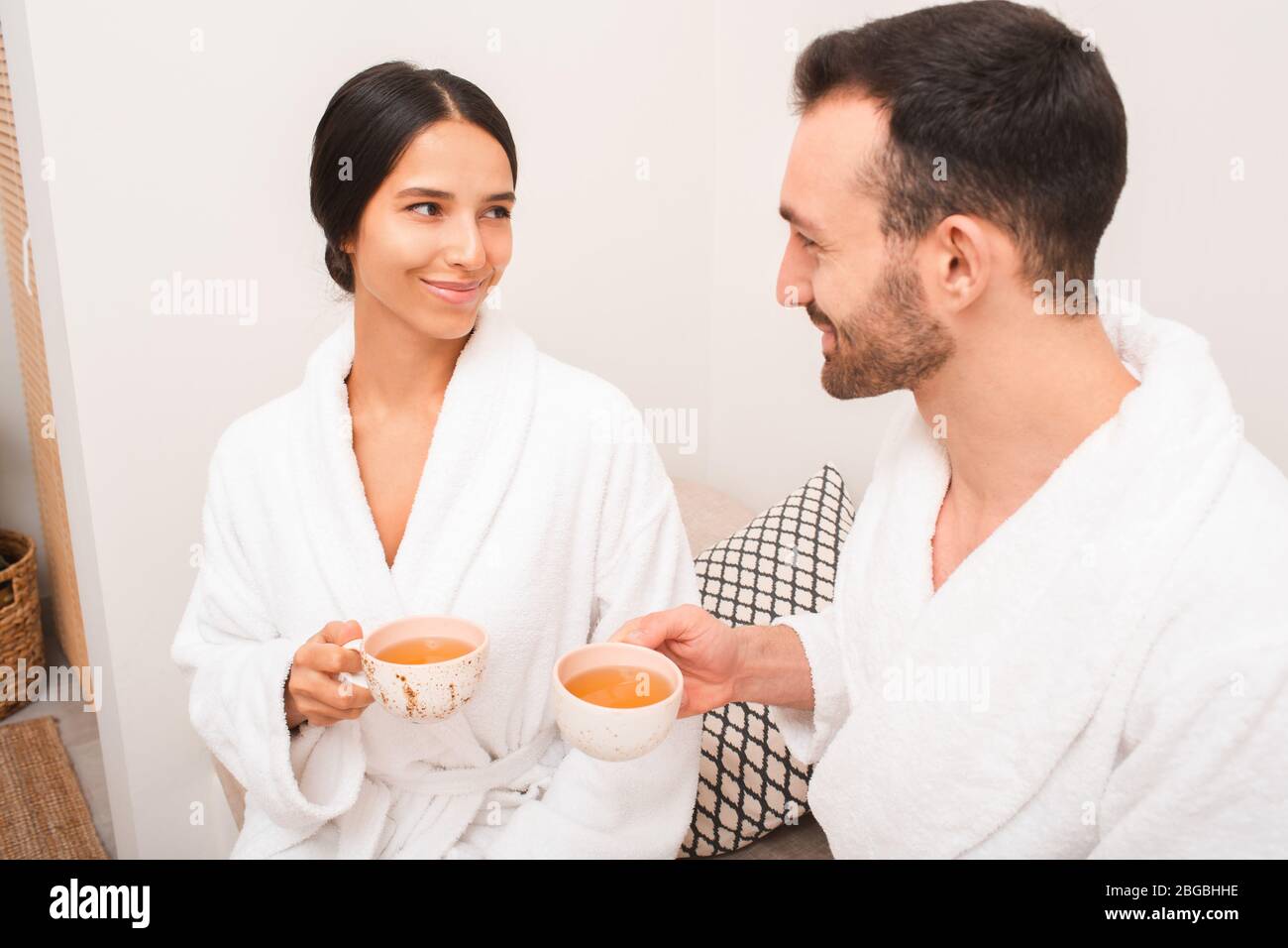 Bella coppia di corse miste bere un tè rilassante in una spa. Appuntamento romantico in un salone termale Foto Stock