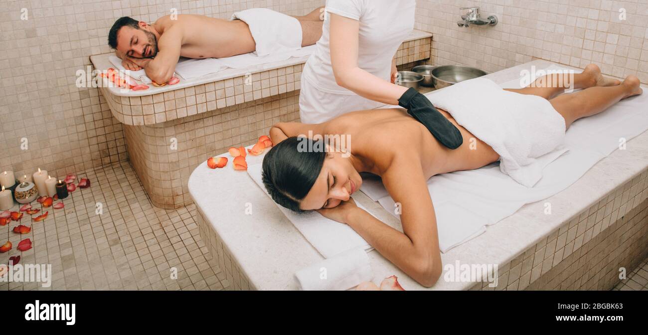 Coppia mista di razza che si spellano la pelle in un hammam turco. GUANTO KESSA peeling in bagno turco Foto Stock