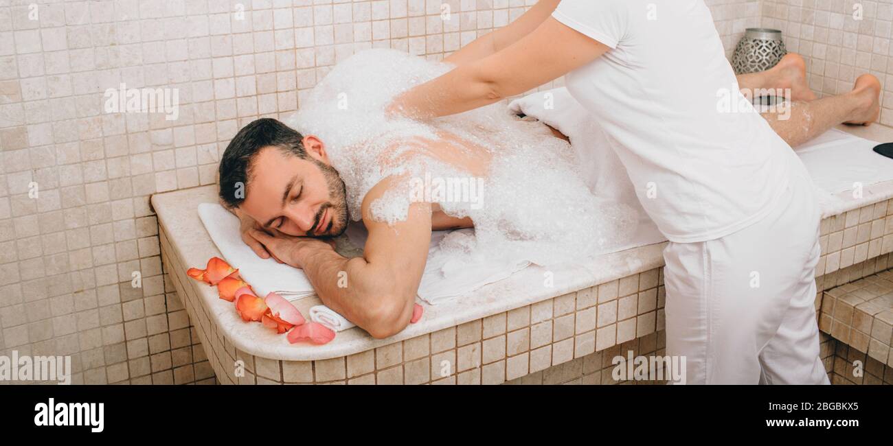 Relax di lusso uomo orientale in bagno turco. L'operatore dell'hammam lava la pelle degli uomini nell'hammam Foto Stock