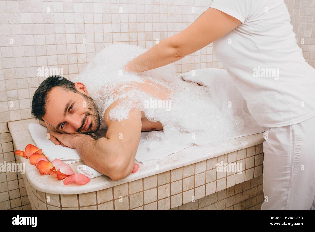 Turco che si gode massaggio in schiuma in un bagno turco. L'operatore dell'hammam lava la pelle degli uomini. Massaggio in schiuma Foto Stock