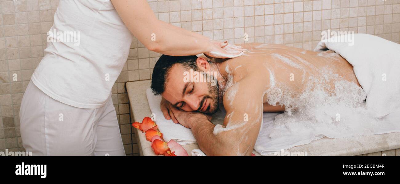 Turco che si gode massaggio in schiuma in un bagno turco. L'operatore dell'hammam lava la pelle degli uomini. Massaggio in schiuma Foto Stock