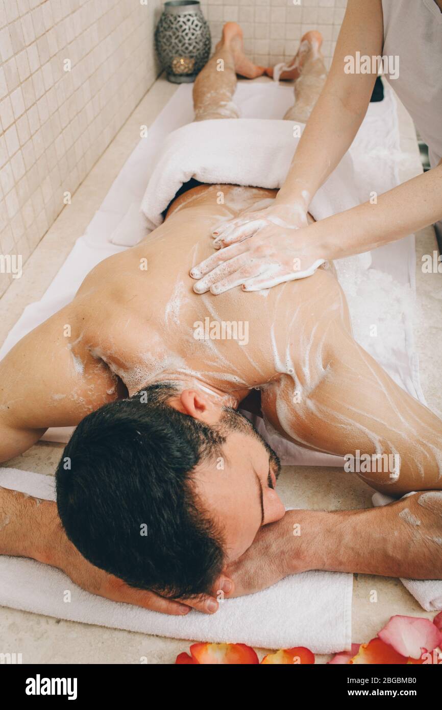 Massaggio al sapone di un bell'uomo in un hammam, vista dall'alto. I trattamenti in bagno turco migliorano le condizioni della pelle e arrestano il processo di invecchiamento. Foto Stock