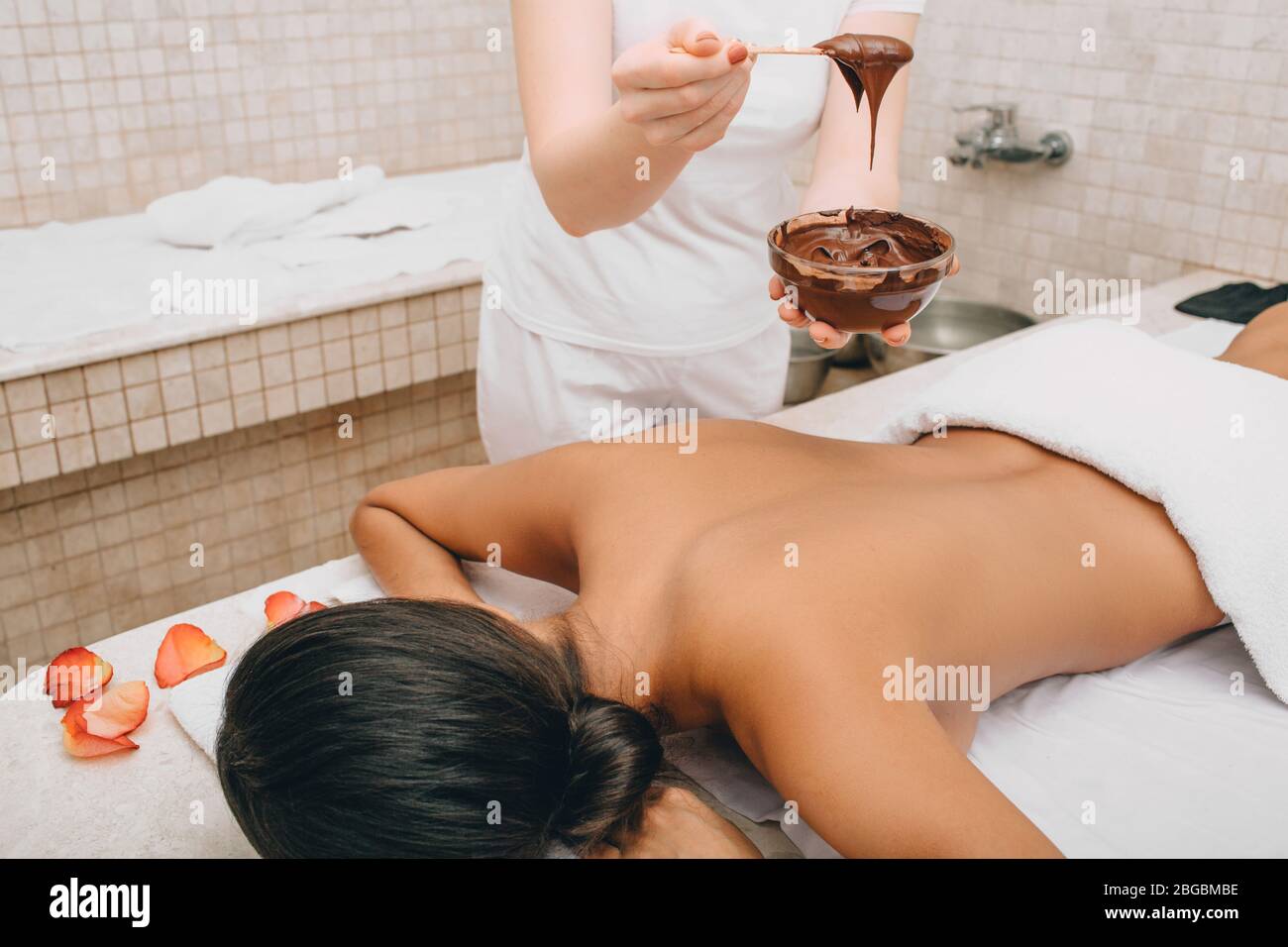Un cioccolatino nel centro benessere. Giovane donna che ottiene una maschera di cioccolato sul suo corpo per idratare la sua pelle Foto Stock